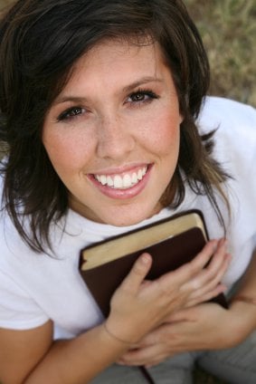 nakangiting babae na may hawak na Bibliya