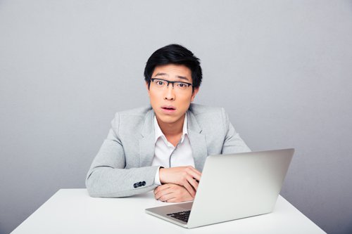 lalaki sa pagkagulat habang nakaupo sa harap ng laptop komputer