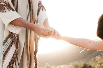 Verlosser hou die hand van die vrou vas wat aan Sy voete neergewerp is. (Johannes 8)