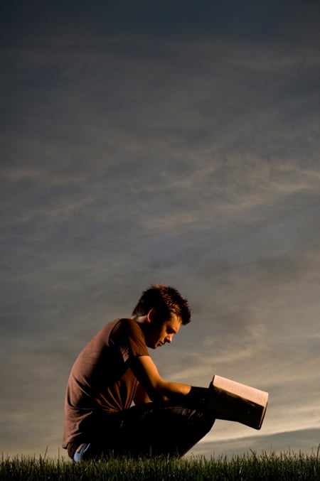 young man kneeling with a Bible