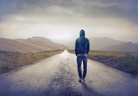 young man walking down a deserted road