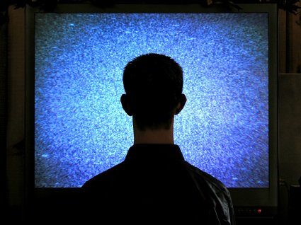 un homme de dos, se tenant stupidement devant un écran plat de télévision.
