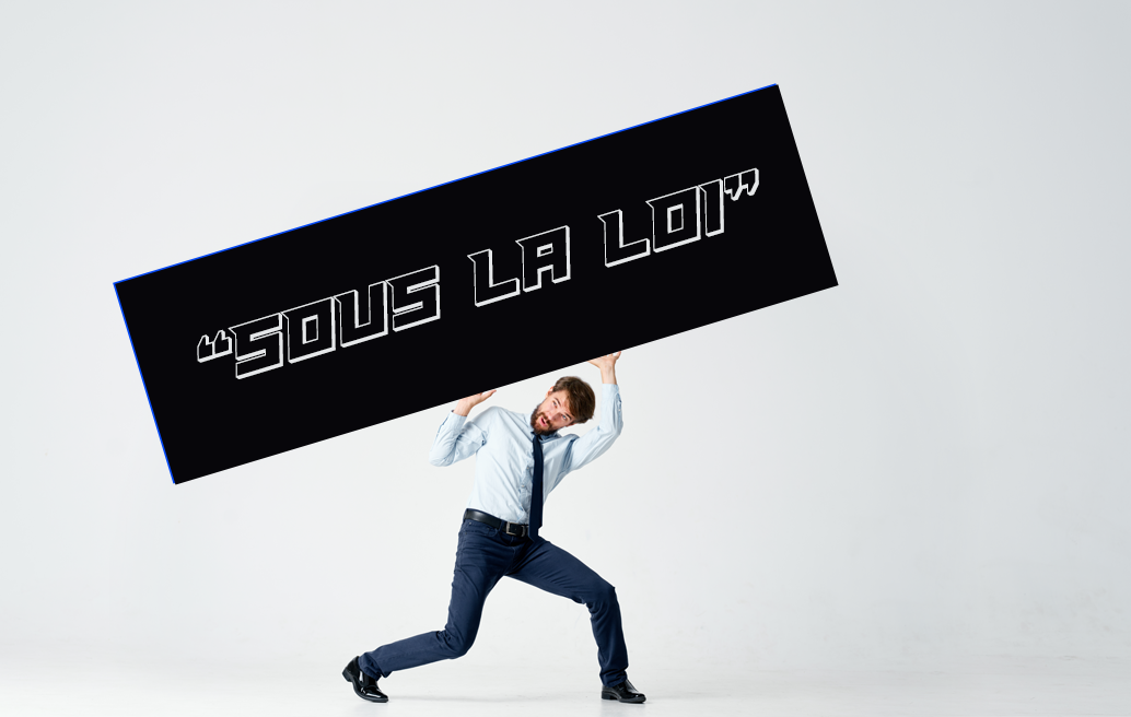 homme bien habillé en chemise cravate ayant de la peine à porter une pancarte portant l’inscription « sous la loi »