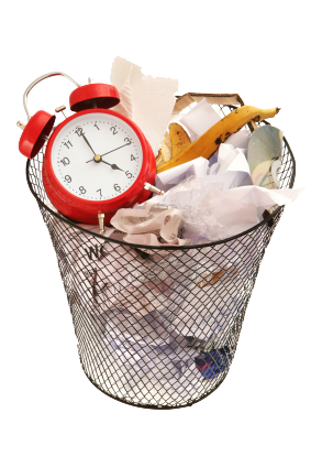 horloge réveil mécanique rouge dans une poubelle métallique grillagée pleine d’ordures : déchets de nourriture, peau de banane, et papiers froissés