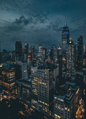 une ville avec des gratte-ciels illuminés, le soir, au début de la nuit, sous un ciel sombre, aux nuages menaçants