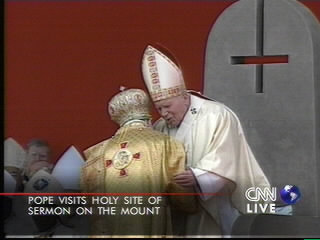 Ioan Paul II stând pe un tron cu crucea răsturnată