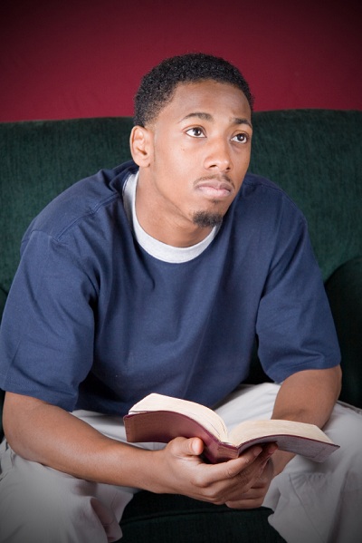 jeune homme contemplatif tenant la Bible en main, les yeux levés vers le Ciel