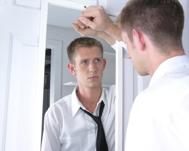 homme en chemise cravate se regardant dans le miroir dans un air pensif et soucieux