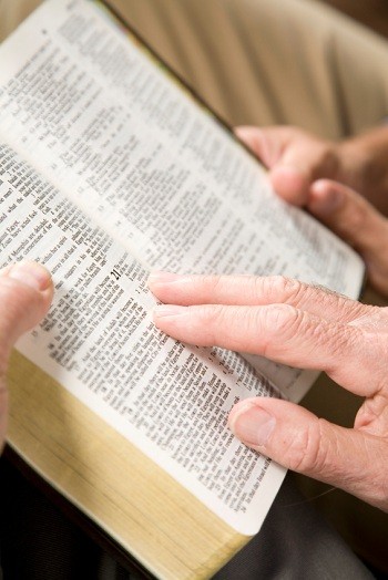 Bible ouverte, tenue à 4 mains, deux personnes faisant lecture et étude biblique.