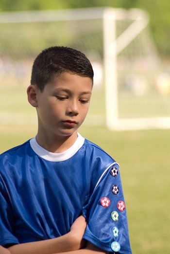 garoto jovem desapontado em uma partida de futebol