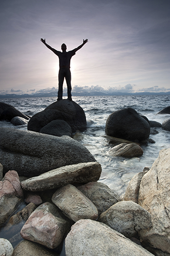 man standing on a rock with arms raised