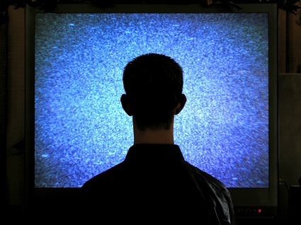man sitting mindlessly in front of television