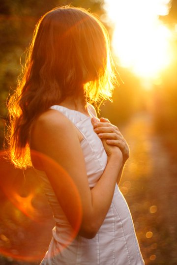 young woman looking back at sunset