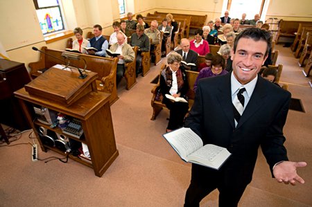 leende pastor med församling i bakgrunden