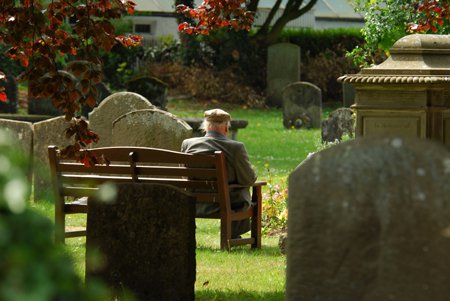 man sitter vid en kyrkogård