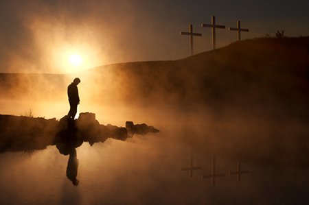 silhouette of a repentant man standing in front of a cross