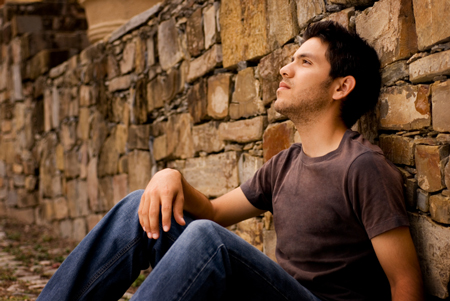 contemplative youn man sitting against a wall