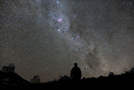 scène de nuit: ombre d’homme, vue de dos, contemplant le ciel étoilé, les constellations de la voie lactée, sur fond d’observatoire astronomique en arrière plan
