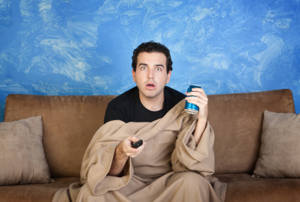 man under blanket sitting in front of television