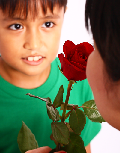 ein Junge überreicht seiner Mama eine Rose