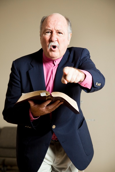 Homme tenant la Bible en pointant du doigt d’un air accusateur.