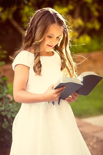 فتاة سعيدة تقرأ الكتاب المقدس