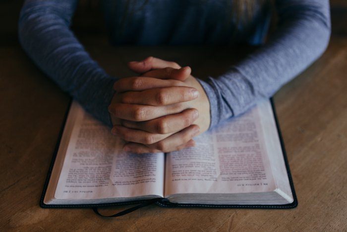 lire la Bible et prier; mains jointes en prière au-dessus d’une Bible ouverte
