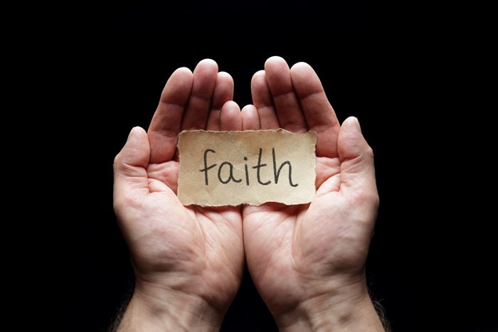 foi, deux mains ouvertes, paumes visibles, mot foi écrit sur un papier au centre, sur fond noir