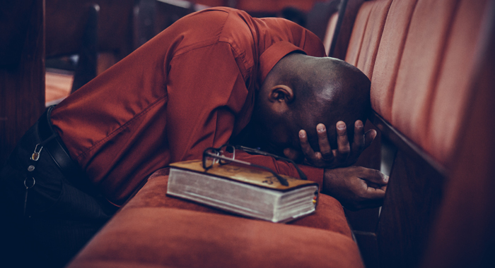 homme priant à côté de sa Bible