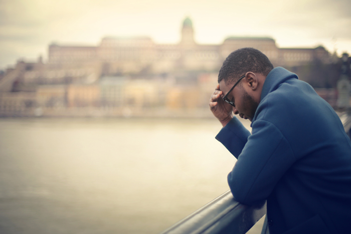homme triste, appuyé sur un pont au dessus de l’eau (rivière, lac, mer, océan, estuaire), tête penchée en avant ; expression de repentance