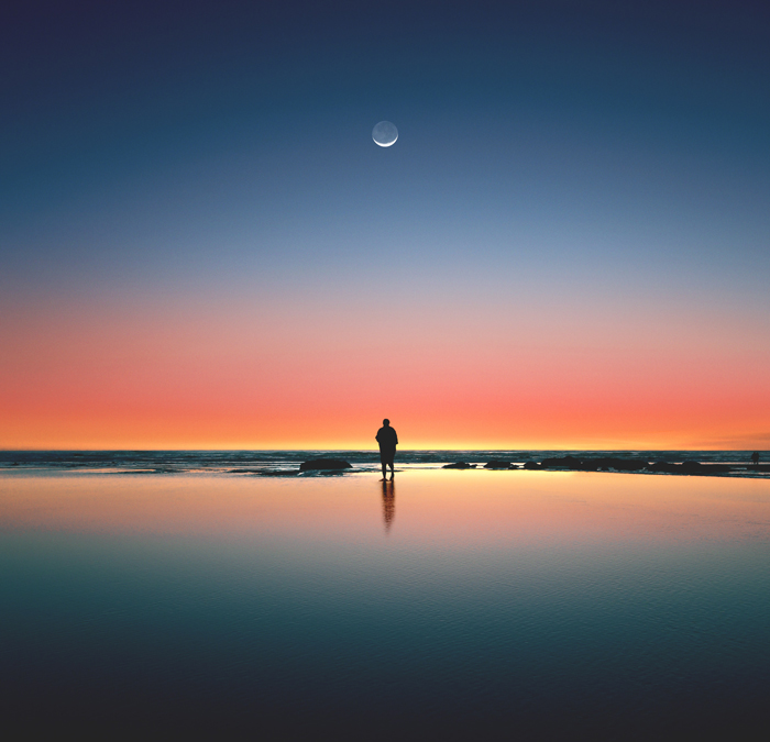 moment individuel au bord de l’océan au coucher du soleil, sous un croissant de lune